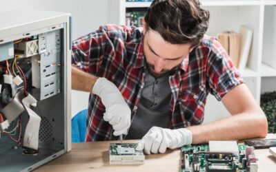 Technicien informatique avec lunettes de protection réparant une carte mère, précision requise similaire à l'entretien d'un TerraMaster U4-500
