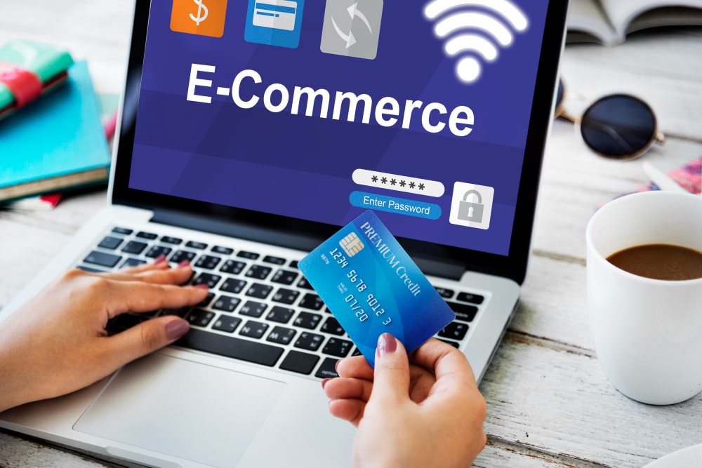 Femme utilisant un ordinateur portable pour l'e-commerce, avec une carte de crédit à la main.