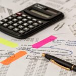 Documents financiers annotés avec des post-it, une calculatrice et des stylos sur une table