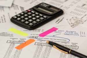 Documents financiers annotés avec des post-it, une calculatrice et des stylos sur une table