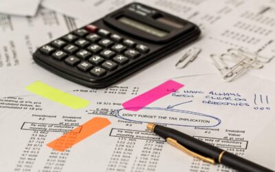 Documents financiers annotés avec des post-it, une calculatrice et des stylos sur une table