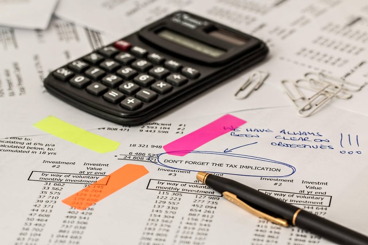 Documents financiers annotés avec des post-it, une calculatrice et des stylos sur une table