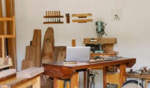 Un atelier de menuiserie avec table, ordinateur, outils et bois