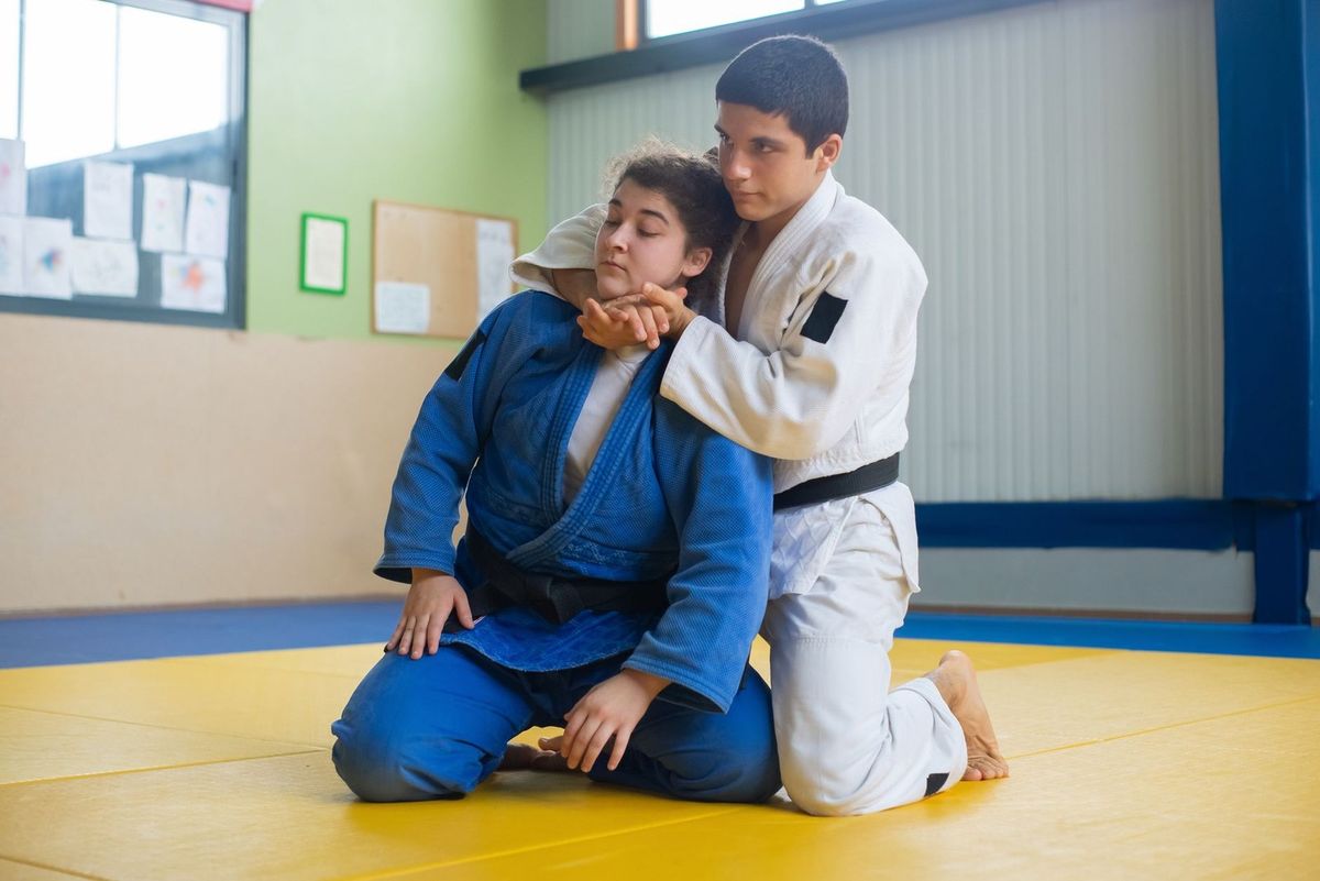 Jeune homme en bleu et autre en blanc pratiquent le judo sur un tatami Jeune homme en bleu et autre en blanc pratiquent le judo sur un tatami