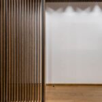 Vue d'un couloir avec paroi en bois ajouré et mur blanc