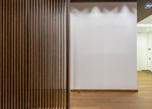 Vue d'un couloir avec paroi en bois ajouré et mur blanc