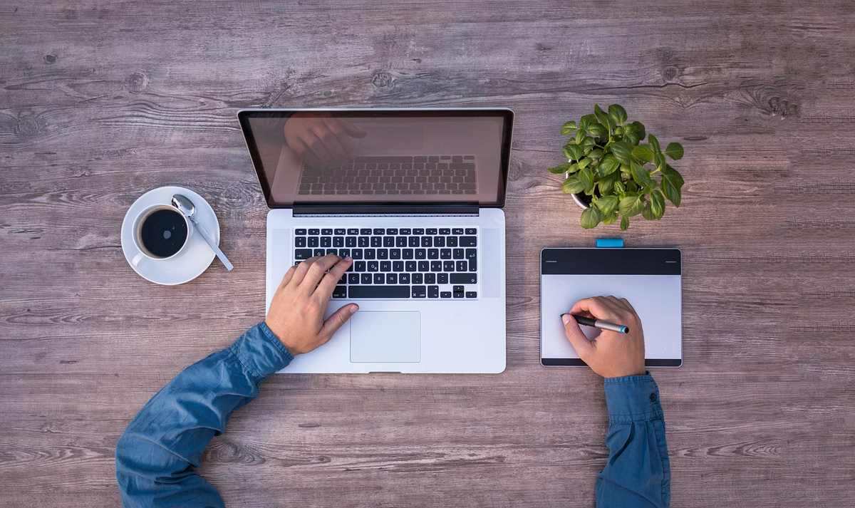 Une personne travaille sur ordinateur portable et utilise une tablette graphique